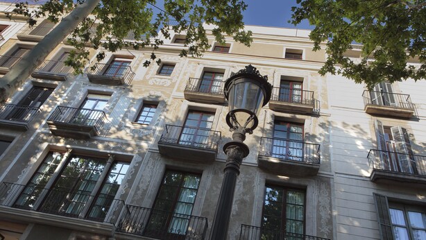 Un edificio con varios balcones, ventanas amplias y un farol de calle.