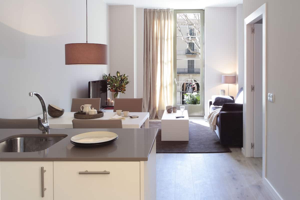 Une cuisine moderne équipée d’un évier, d’un coin repas avec une table et des chaises, et offrant une vue sur l’extérieur grâce à une fenêtre.