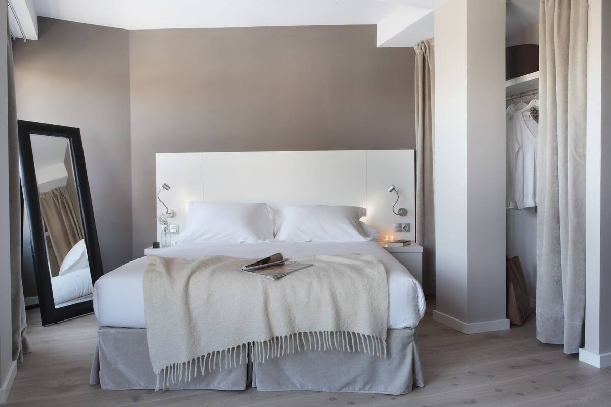 Une chambre moderne avec un grand lit, des lampes de chevet, un miroir et une armoire.