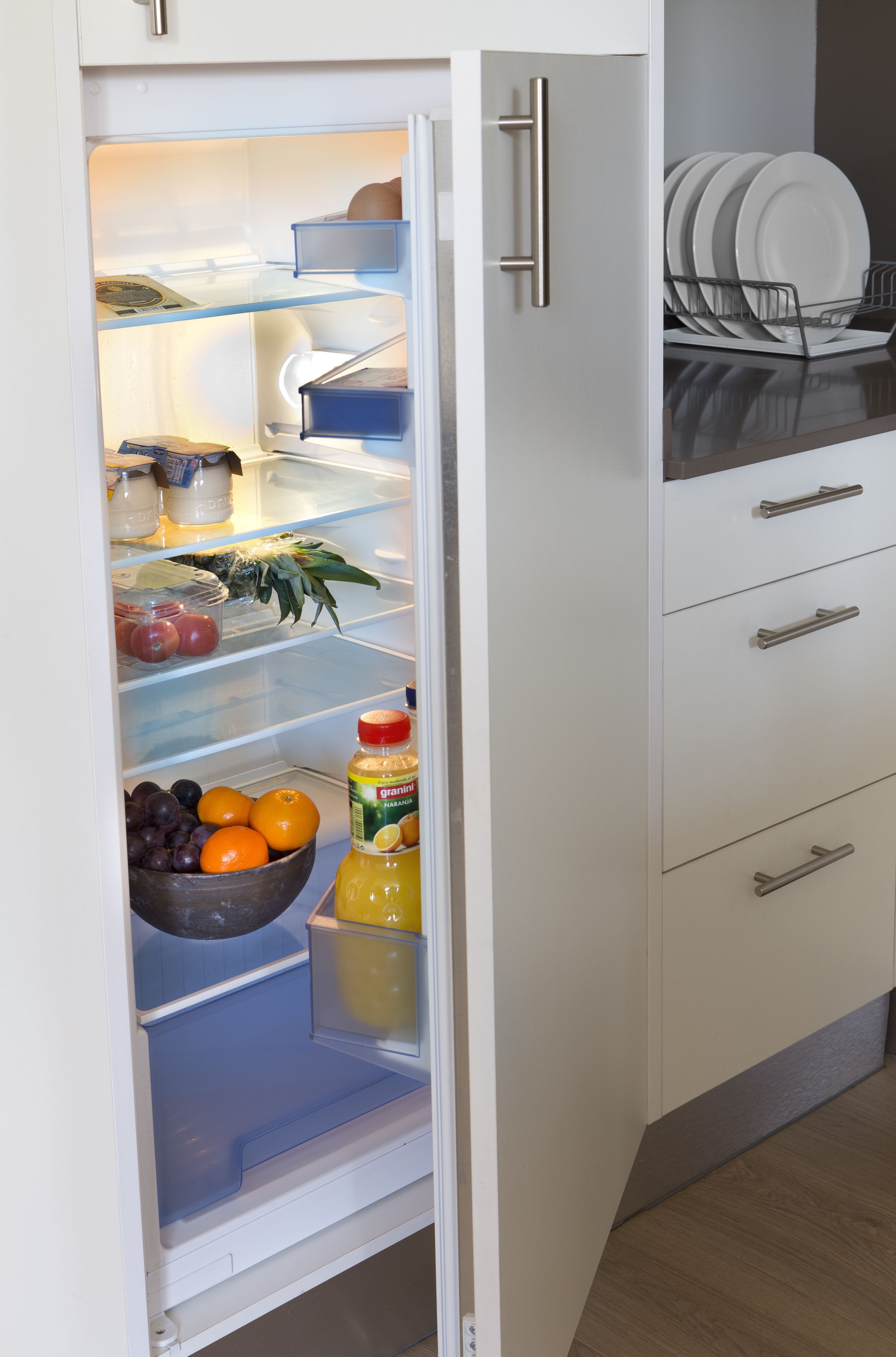A refrigerator with shelves containing fruits, vegetables, and a bottle of juice.