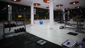 Un gimnasio con equipo de ejercicio, una pelota de gimnasia azul y una báscula.