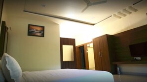 Una habitación de hotel con una cama, ventilador de techo, un cuadro en la pared y un armario.