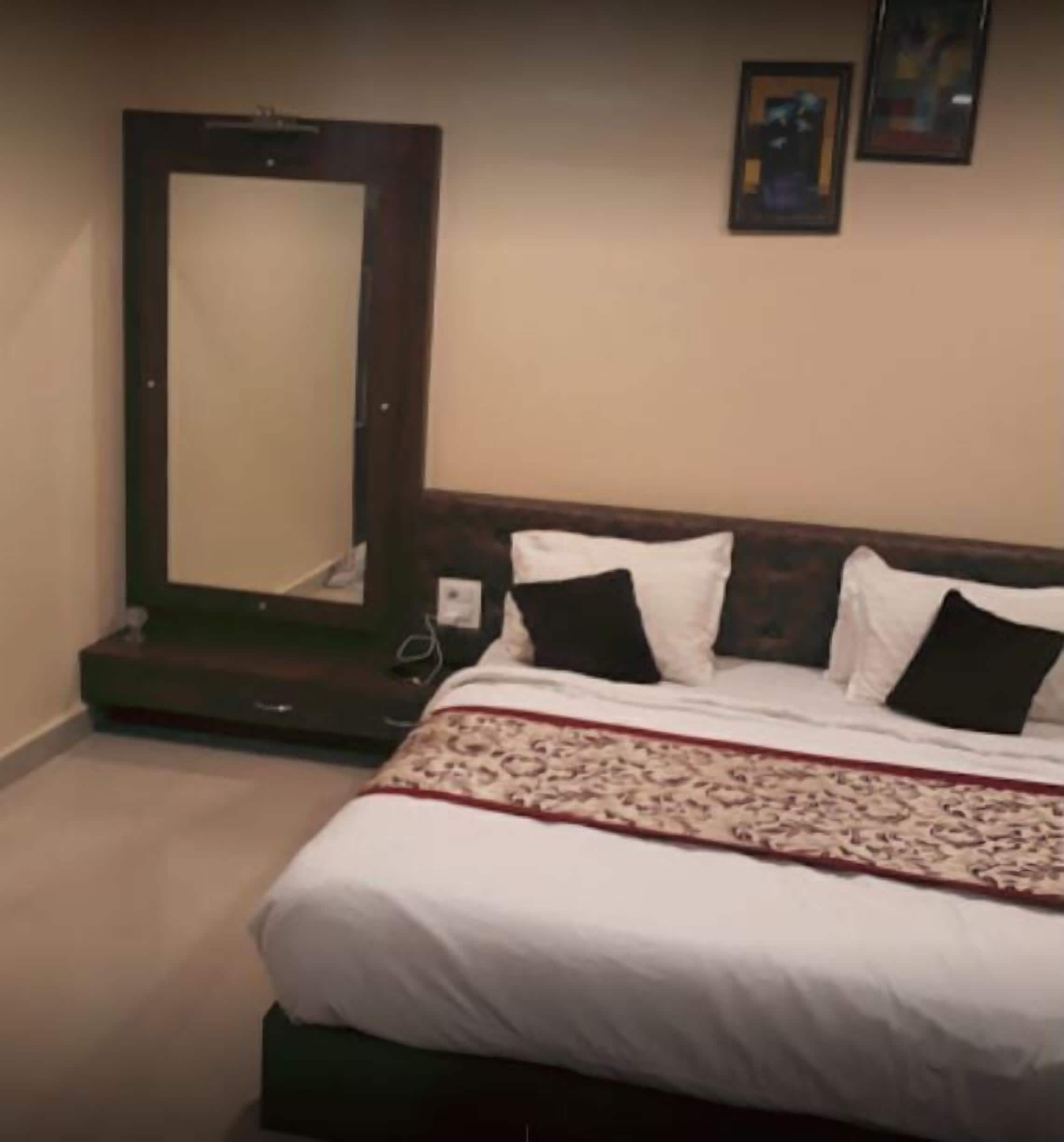 A bedroom with a bed, a mirror, and a picture on the wall.