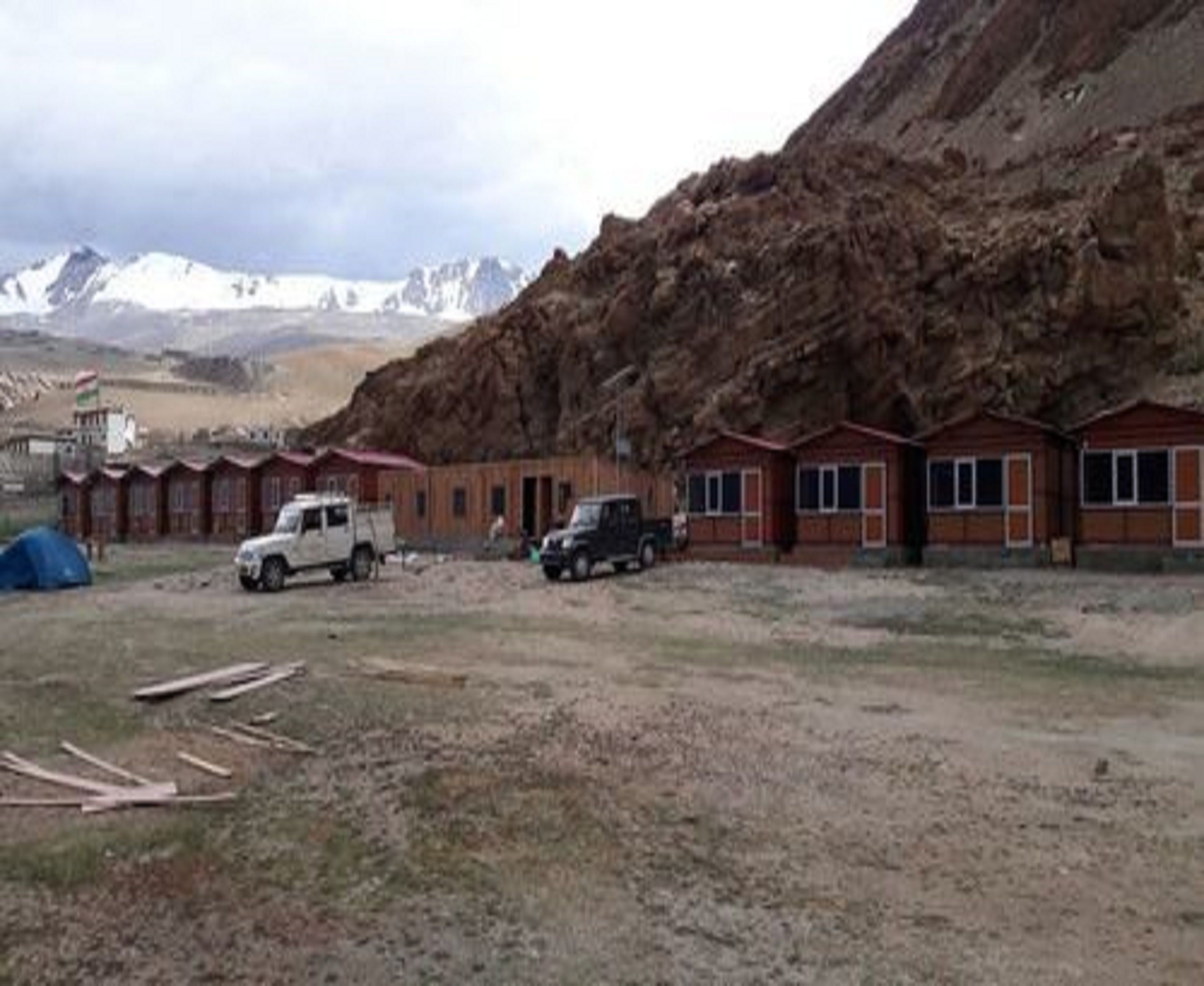 Un hilera de cabañas de madera con montañas al fondo.