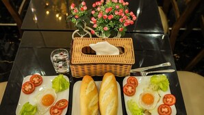 A table with two plates of eggs and tomatoes, a basket, and a vase of flowers.