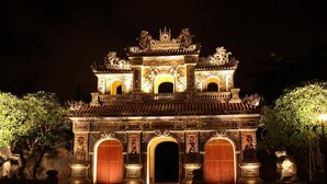 A traditional ornate gate with multiple arches and intricate carvings, illuminated at night.