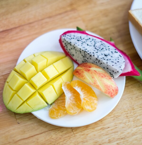 Un plato con mango en rodajas, pitahaya y gajos de naranja.