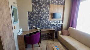 A modern living room with a wooden desk, purple chair, sofa, and a coffee table. - Udi Hotel (Çanakkale)