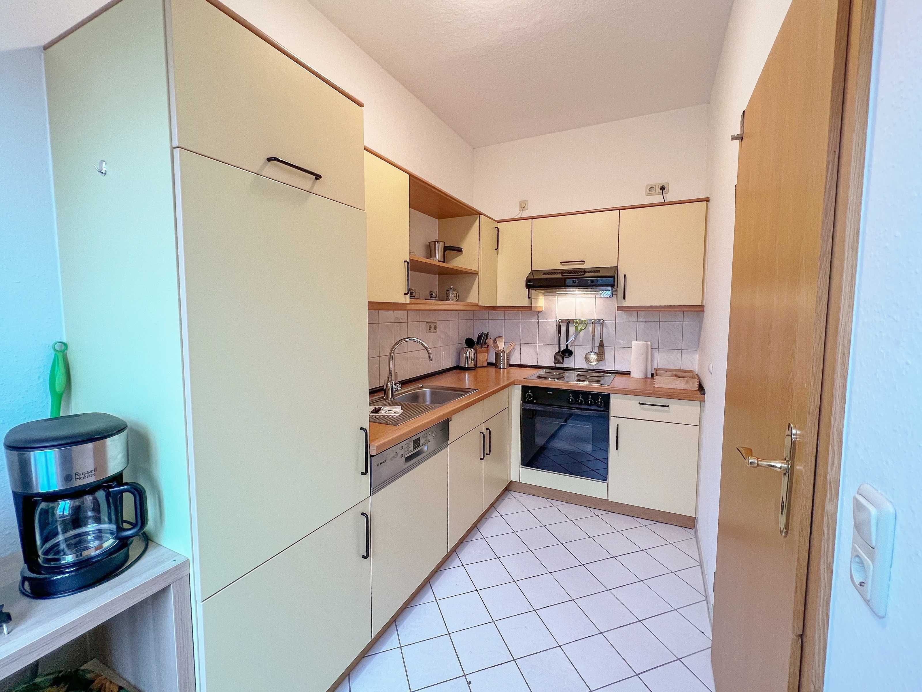 A compact kitchen with a built-in oven, a coffee maker, and a sink.