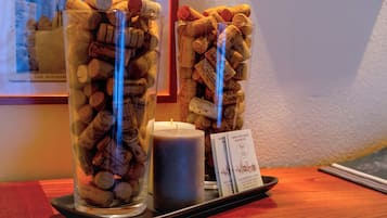 Deux récipients en verre remplis de bouchons de bouteilles de vin, une bougie et une petite carte, le tout disposé sur un plateau.