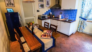 A compact kitchen with a dining area, featuring a microwave, sink, and a small refrigerator. - Palazzo Mari (San Gimignano)