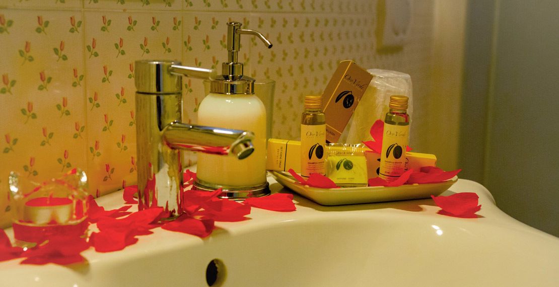 A bathroom sink with toiletries and rose petals.