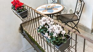 A small outdoor seating area with a round table and chairs, surrounded by metal railings. - Palazzo Mari (San Gimignano)