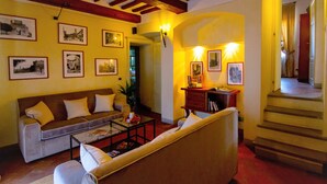A living room with a sofa, coffee table, and framed pictures on the wall. - Palazzo Mari (San Gimignano)