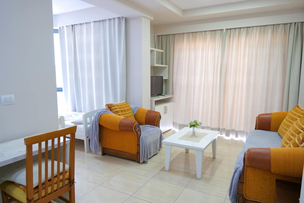 A living room with two sofas, a coffee table, a TV stand, and a dining table.
