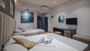 Una habitación de hotel moderna con dos camas, un escritorio, un televisor de pantalla plana y obras de arte en las paredes.