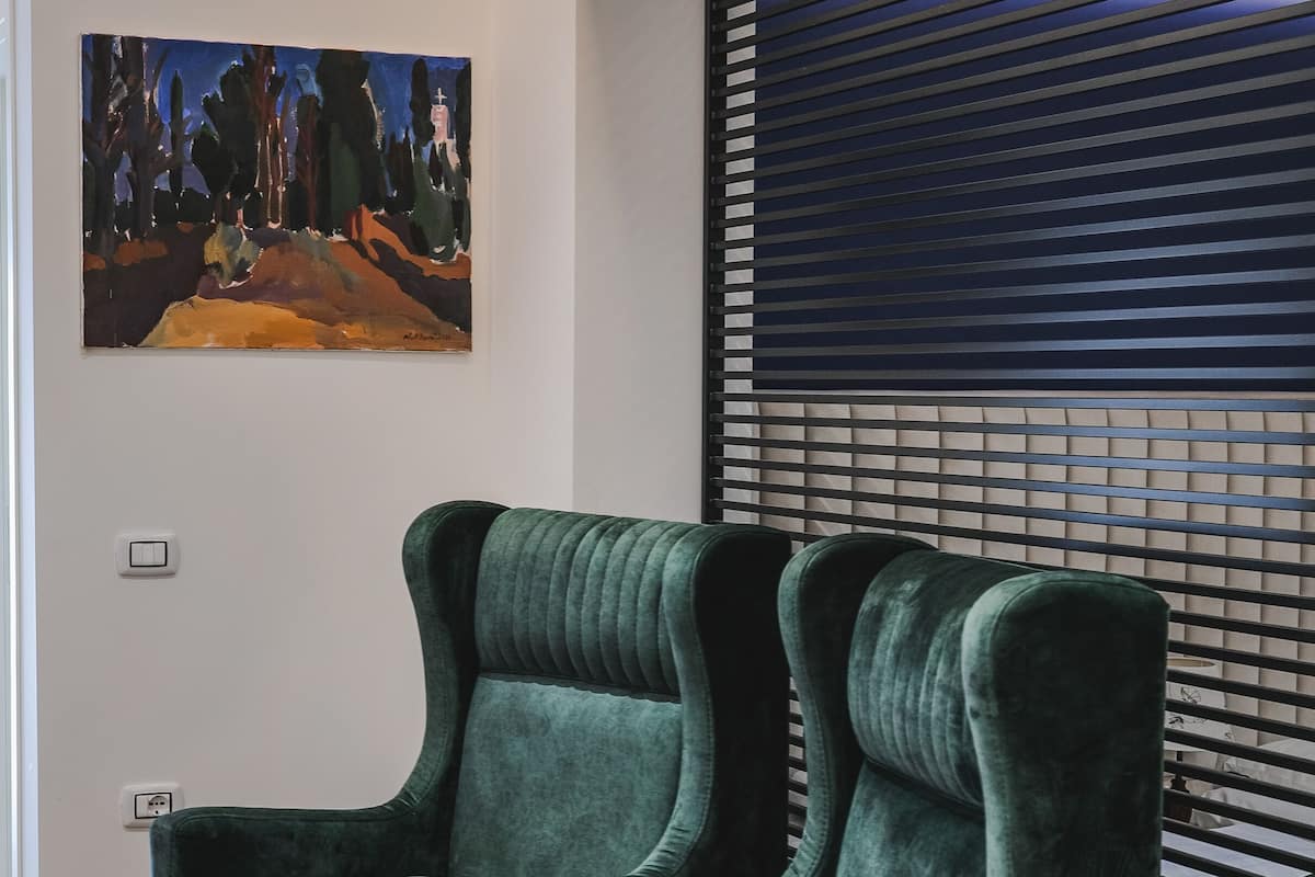 A modern living room with a green sofa, a small table, and a painting on the wall.
