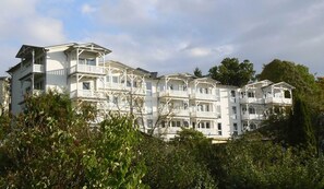 Un hôtel à plusieurs étages, doté de balcons et d’une façade blanche.
