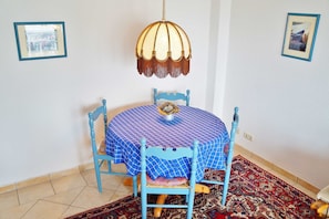 Un coin repas avec une table ronde recouverte d’une nappe à carreaux bleus, entourée de chaises bleues.