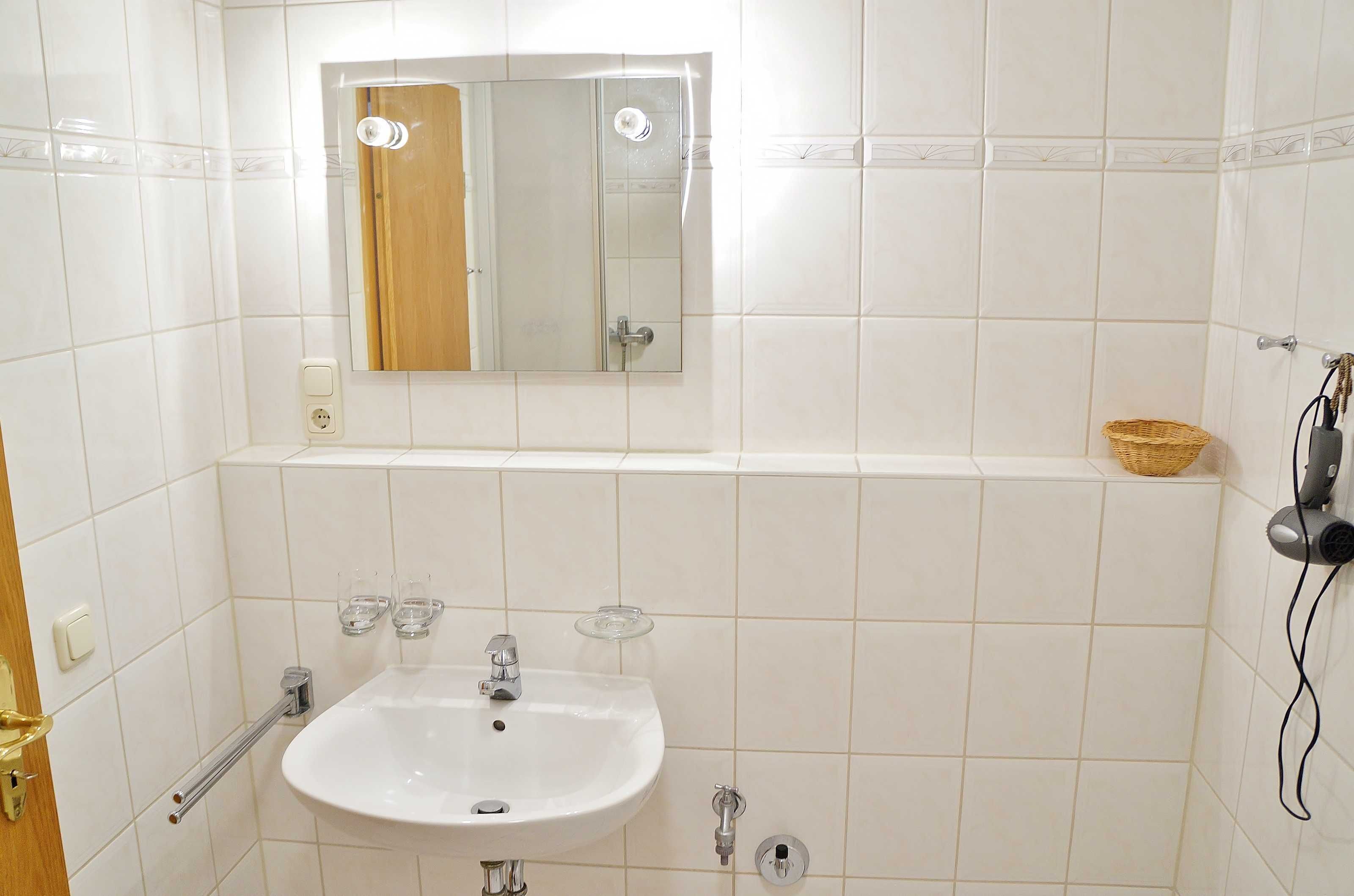 A bathroom with a white sink, mirror, and a shelf with a basket.