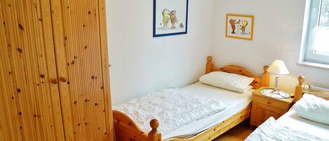 Un dormitorio con una cama de madera, una mesita de noche con una lámpara y dos cuadros en la pared.