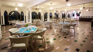 A spacious dining area with multiple tables and chairs, large arched windows, and a tiled floor. - CityBlue Creekside Hotel & Suites, Mombasa (Mombasa)