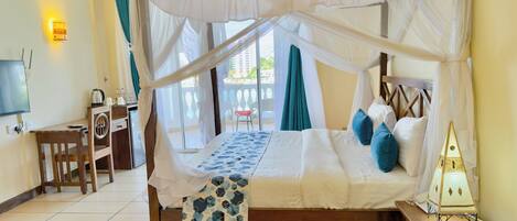 A room with a bed, a desk, a TV, and a balcony with a chair.
