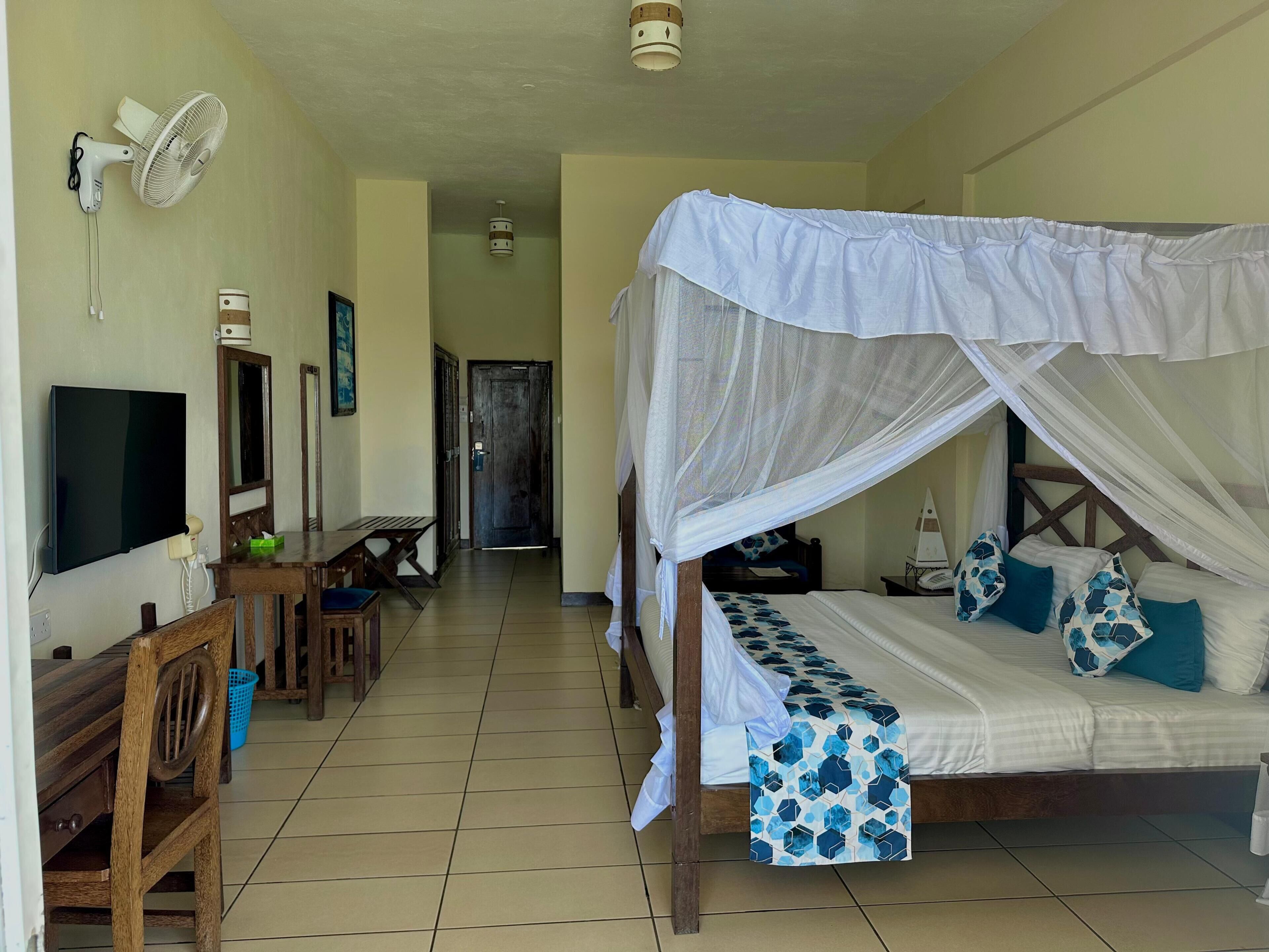 A bedroom with a bed, a TV, a desk, and a chair.