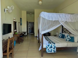 Un dormitorio con cama, televisión, escritorio y silla.