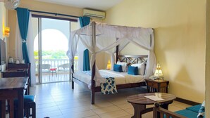 Habitación de hotel con cama con dosel, balcón con sillas, una mesita y una lámpara.