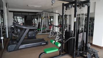 Une salle de sport équipée de tapis de course, d’appareils de musculation et d’un banc.