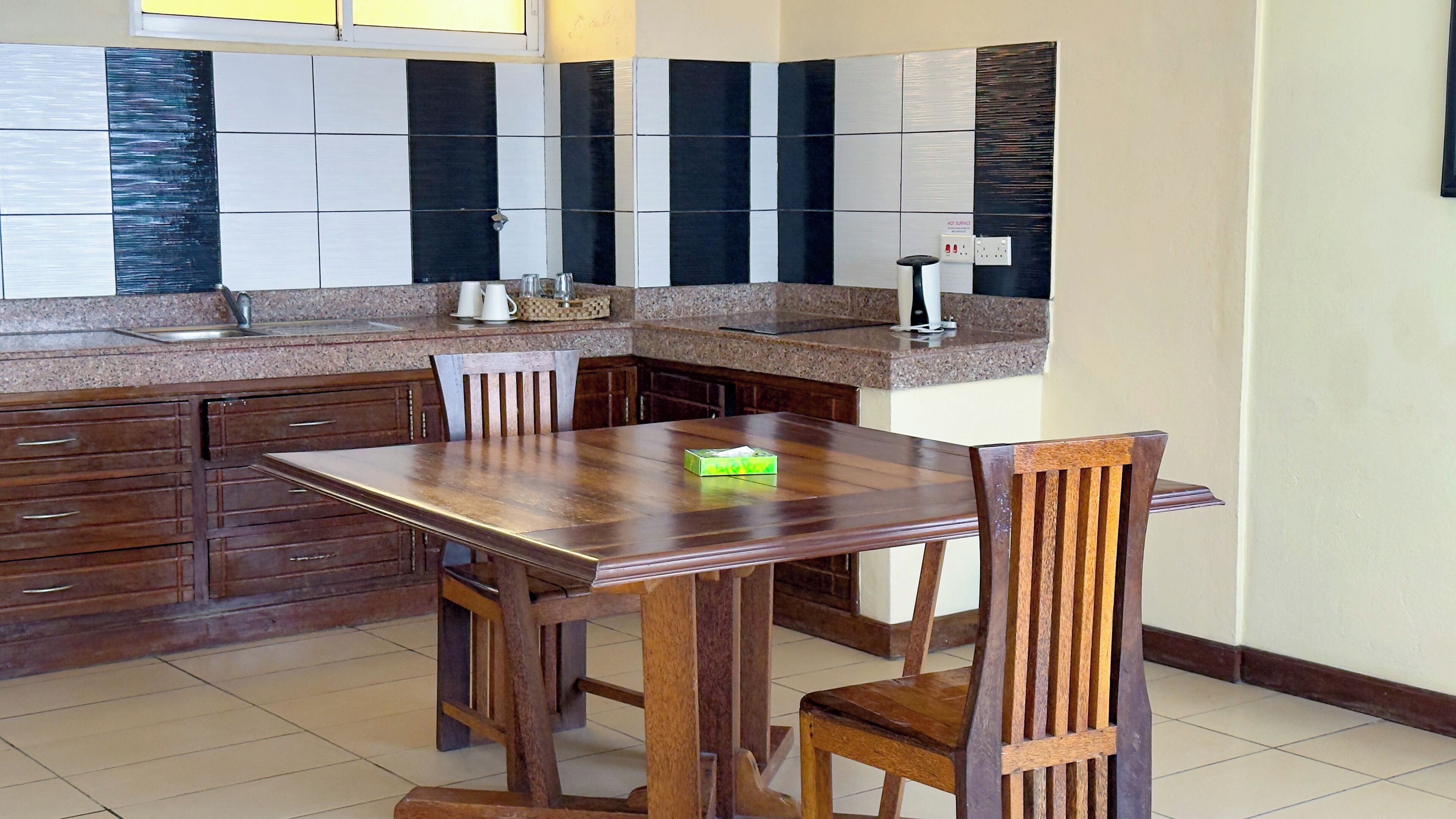 A kitchen with a dining table, chairs, cabinets, and a countertop.