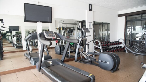 Un gimnasio con cintas de correr, elípticas y pesas.