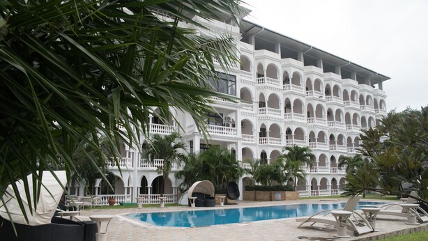 Un edificio grande con varios balcones y un área de piscina con sillones y sombrillas.