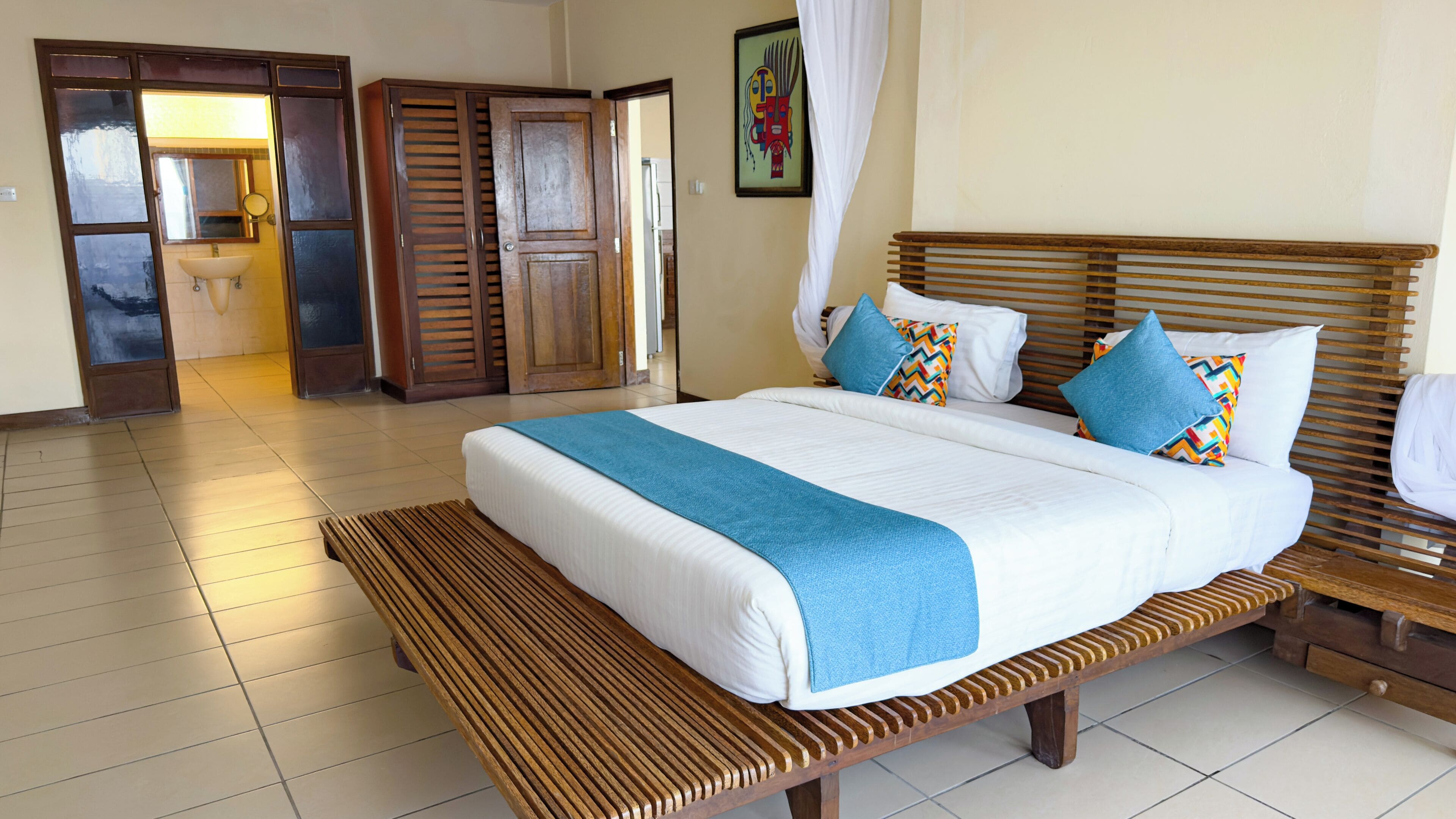 A hotel room with a large bed, wooden headboard, and a bench.