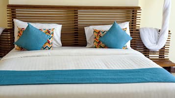Un letto con una testiera in legno, lenzuola bianche e due cuscini decorativi con motivo geometrico.