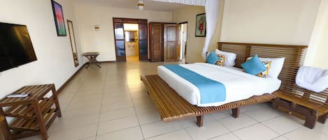 A hotel room with a bed, wooden headboard, bedside tables, a bench, and a television.