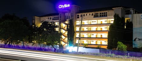 Ein mehrstöckiges Hotel mit einem gut sichtbaren 'CityBlue'-Schild, inklusive Balkonen und einer zentralen Treppe.
