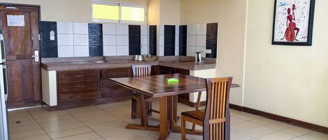 A kitchen with a wooden table and chairs, a window, and a painting on the wall.