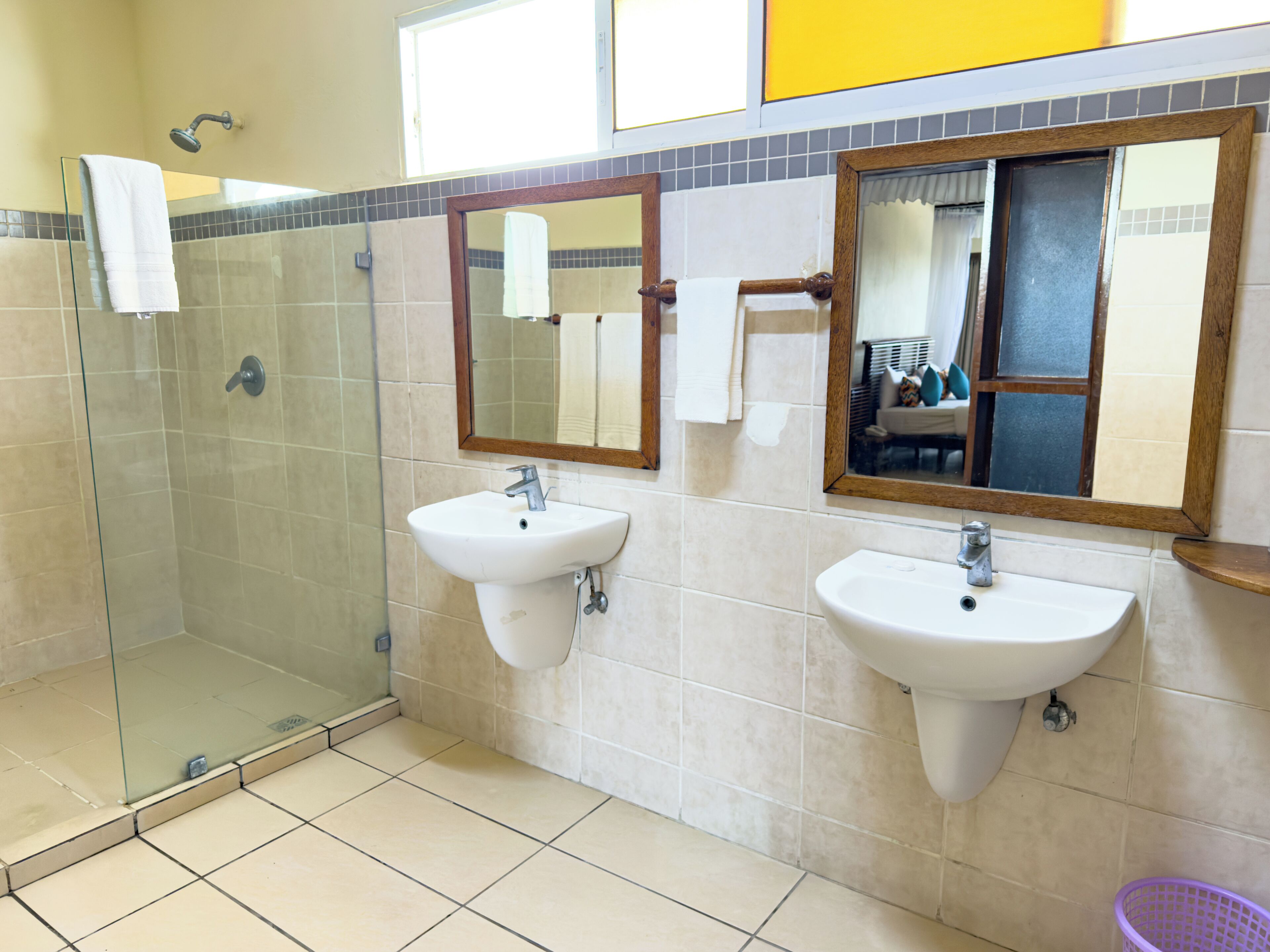 A bathroom with two sinks, a glass shower enclosure, and mirrors.