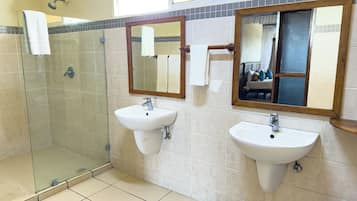 Un baño con dos lavamanos, cabina de ducha de vidrio y espejos.