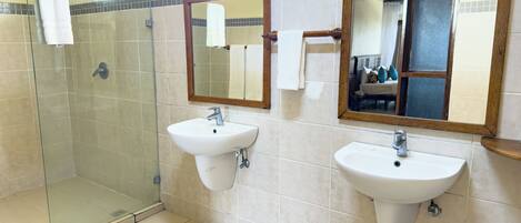 A bathroom with two sinks, a glass shower enclosure, and mirrors.