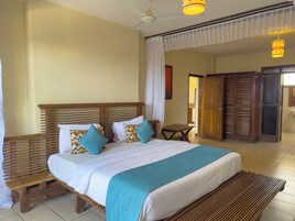 Una habitación de hotel con una cama grande, cabecera de madera y un banco.