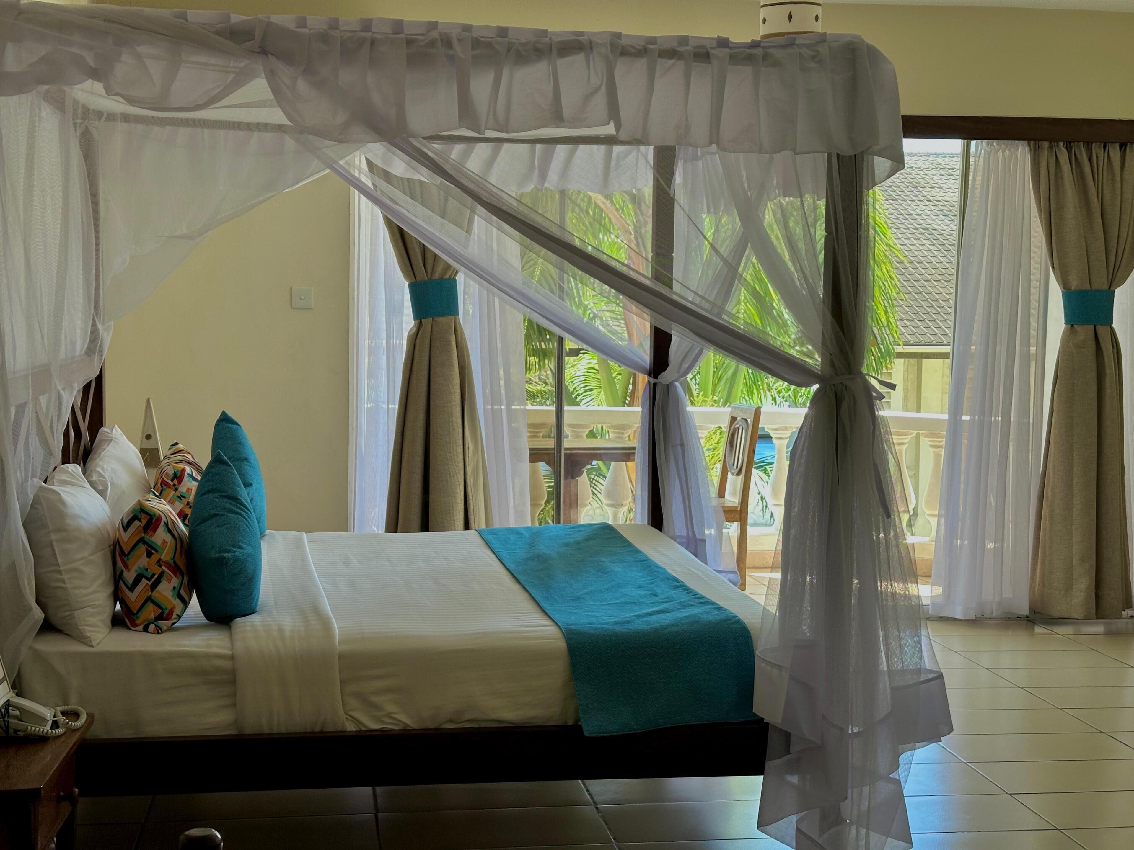 A bed with a canopy, pillows, and a telephone on a bedside table.