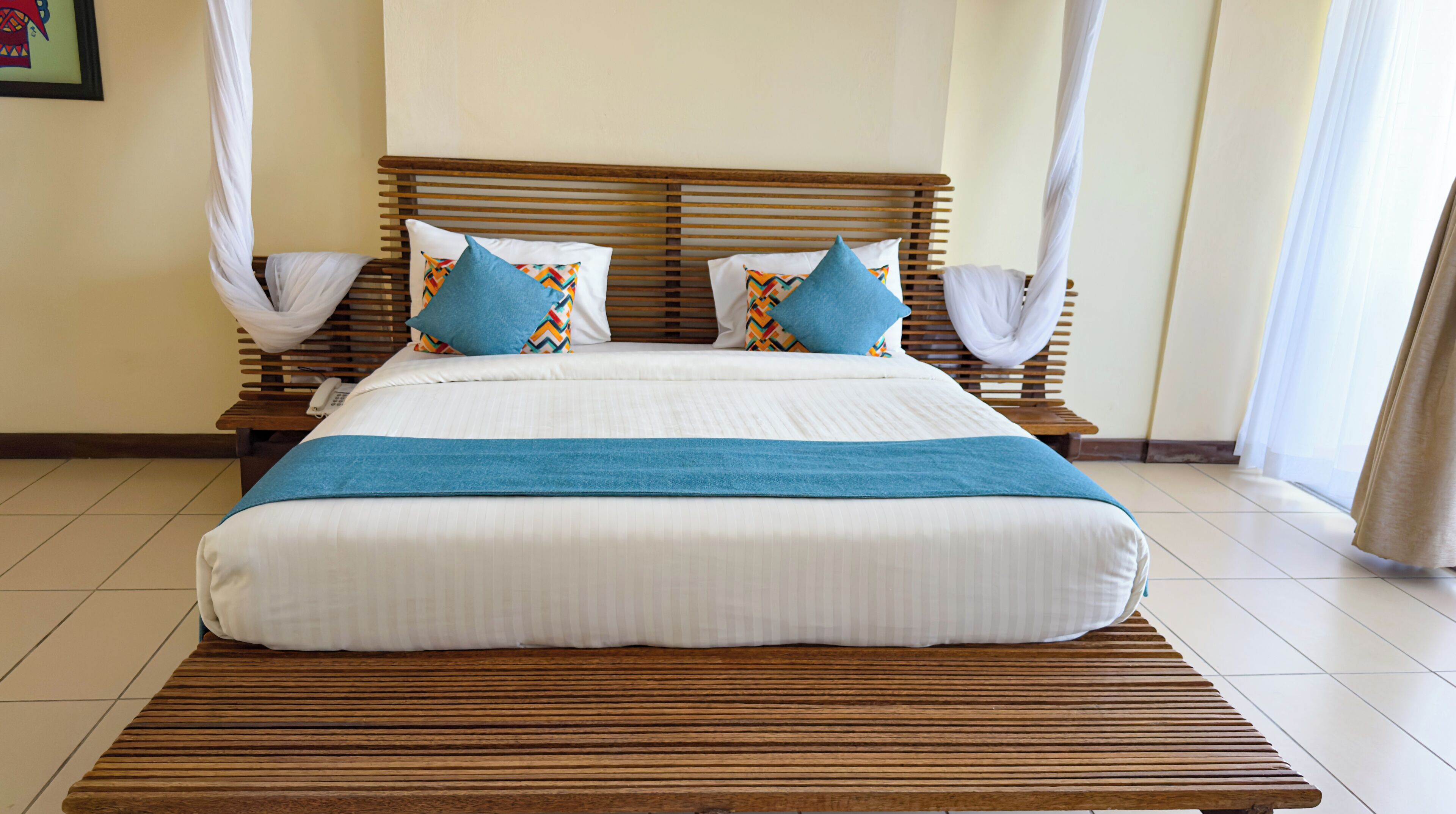 A bed with a wooden frame, white bedding, and blue pillows.