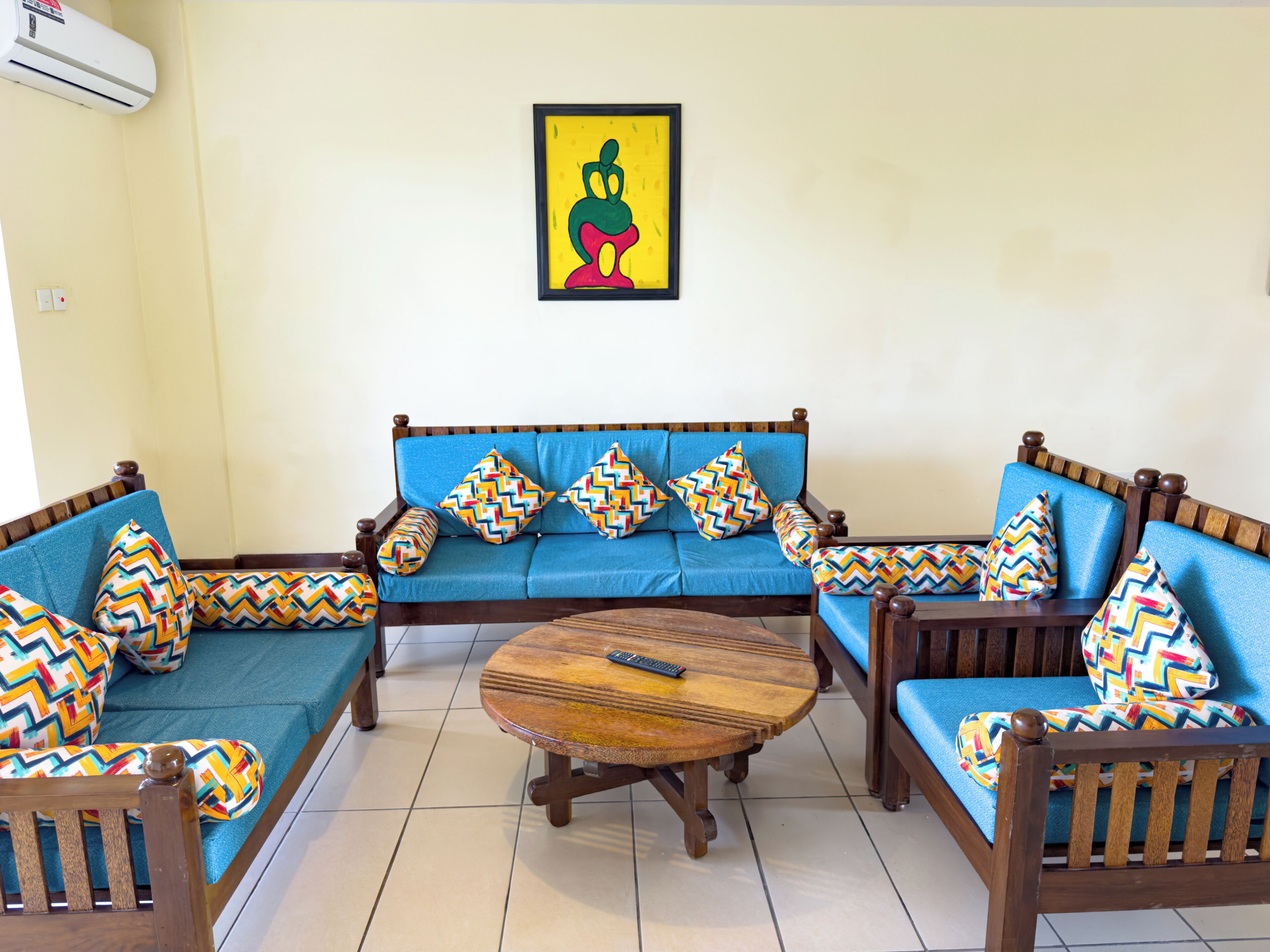 A living room with a sofa set, a coffee table, and a wall-mounted air conditioner.