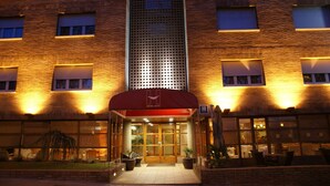 A hotel entrance with a red awning, a central vertical ventilation shaft, and a brick facade. - Hotel Estel (Berga)