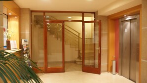 A hotel lobby with a glass door entrance, a staircase, and an elevator. - Hotel Estel (Berga)