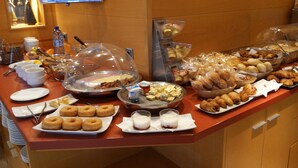 A buffet with various food items and a television screen displaying a news program. - Hotel Estel (Berga)