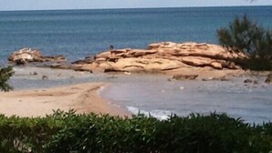 Ein Strand mit Felsformationen und freiem Blick auf das Meer.